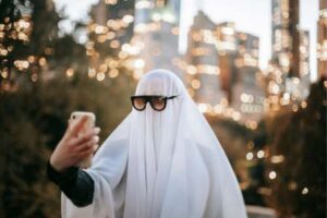 Eine Person verkleidet als Geist macht ein Selfie, symbolisiert das Problem des Ghosting beim Online-Dating.