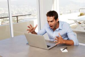 Ein frustrierter Mann sitzt vor seinem Laptop und hat Schwierigkeiten bei der Registrierung auf einer Dating-App.