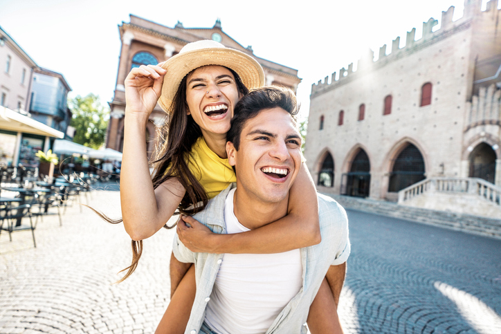 Lachendes Paar in einer mediterranen Stadt, das gemeinsam Spaß hat – Symbolbild für eine Situationship, die sich zwischen Freundschaft und Liebe bewegt.