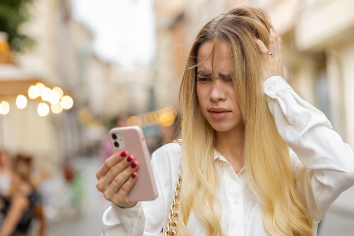 Frau schaut verwirrt auf ihr Handy und stellt fest, dass Dating-Apps ihren Reiz verlieren