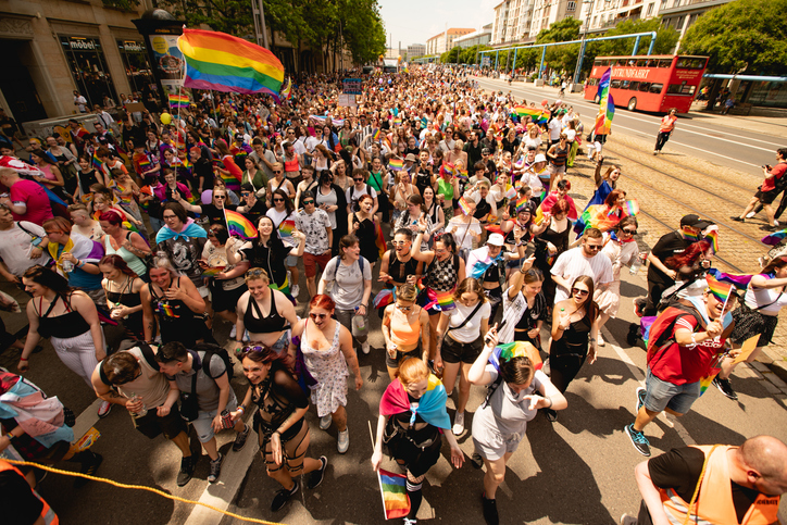 Große LGBTQ+-Demonstration mit Regenbogenflaggen und Menschen, die für ihre Rechte auf die Straße gehen. Symbol für Vielfalt, politische Teilhabe und Aktivismus.