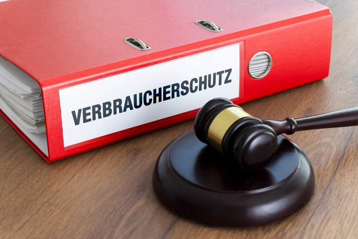 Roter Ordner mit der Aufschrift „Verbraucherschutz“ und ein Richterhammer auf einem Holztisch