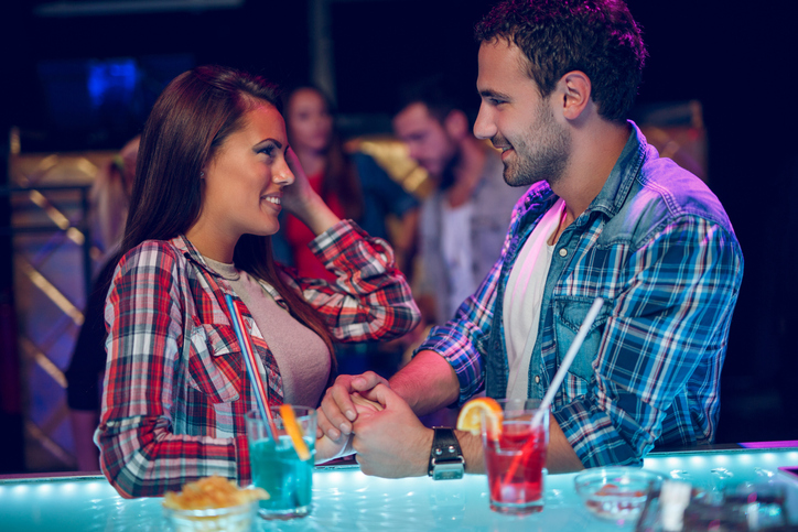 Mann und Frau beim ersten Date an einer Bar diskutieren lächelnd über die Rechnung