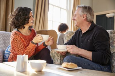 Mann und Frau mittleren Alters lachen beim Kaffee und genießen ein Gespräch